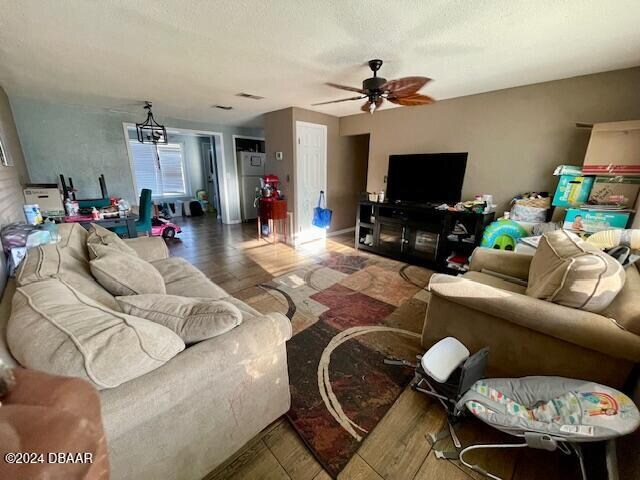 living room featuring ceiling fan with notable chandelier and dark hardwood / wood-style floors