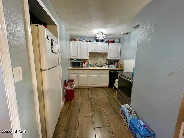 kitchen featuring tasteful backsplash, stainless steel appliances, white cabinetry, sink, and light hardwood / wood-style flooring