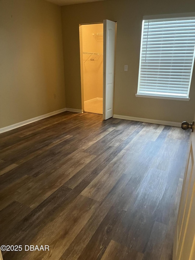 940 Village Trl Unit 6-109, Port Orange, FL 32127 - unfurnished bedroom featuring dark wood-style flooring, a spacious closet, baseboards, and a closet