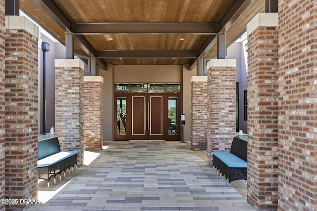 view of exterior entry with brick siding, stucco siding, and french doors