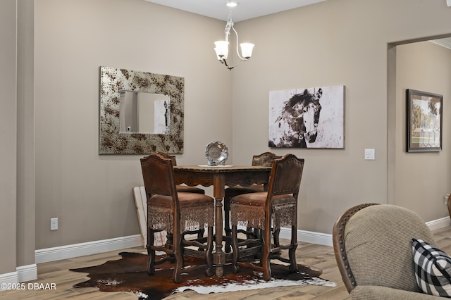 dining space featuring baseboards, wood finished floors, and a chandelier