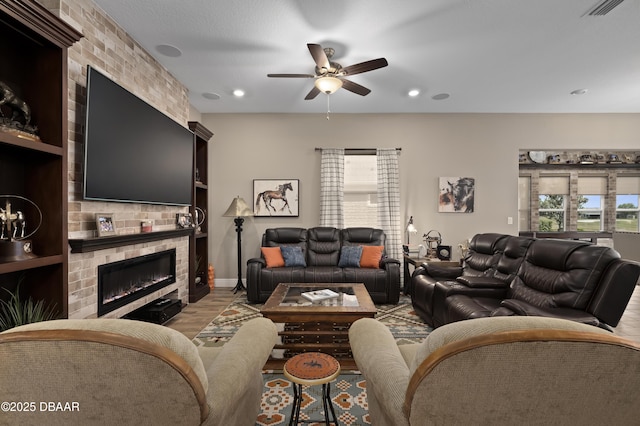 living room featuring ceiling fan, visible vents, a fireplace, wood finished floors, and recessed lighting