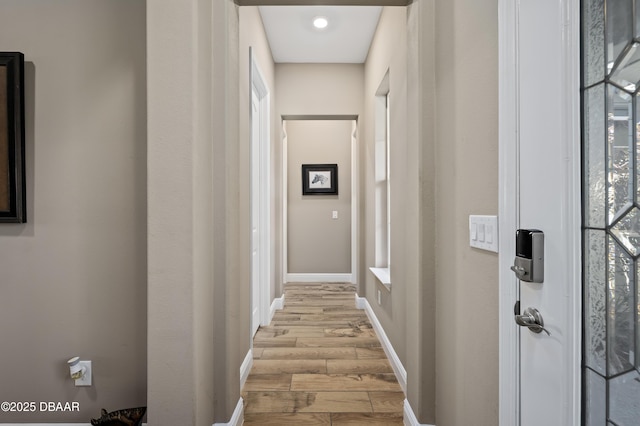 hall with baseboards and light wood finished floors