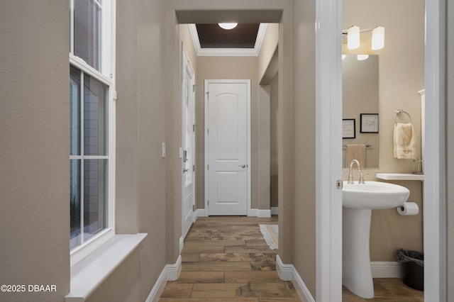corridor with crown molding, baseboards, and wood finished floors