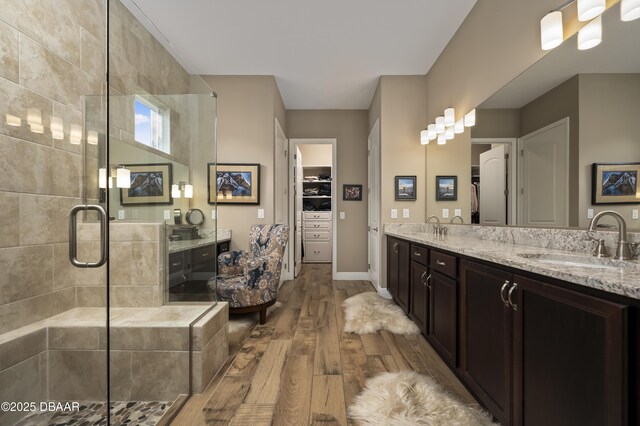 full bathroom with double vanity, a shower stall, a sink, and hardwood / wood-style floors