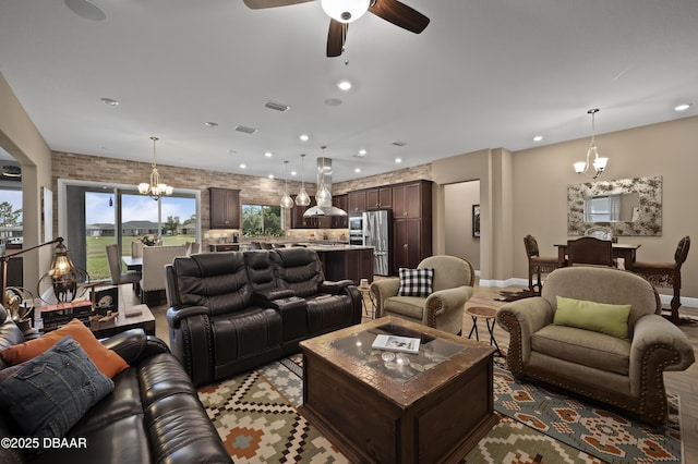 living area featuring recessed lighting, baseboards, ceiling fan with notable chandelier, and visible vents