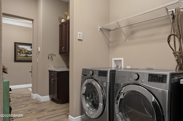 clothes washing area featuring baseboards, cabinet space, light wood-type flooring, and independent washer and dryer