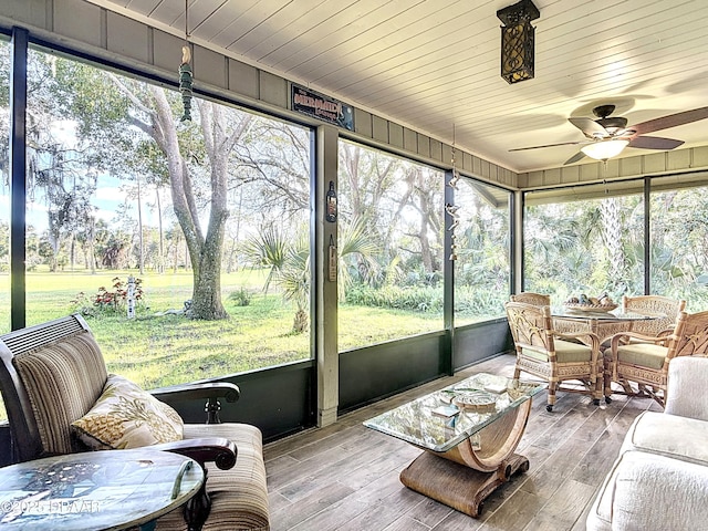 sunroom featuring wooden ceiling, a ceiling fan, and a healthy amount of sunlight