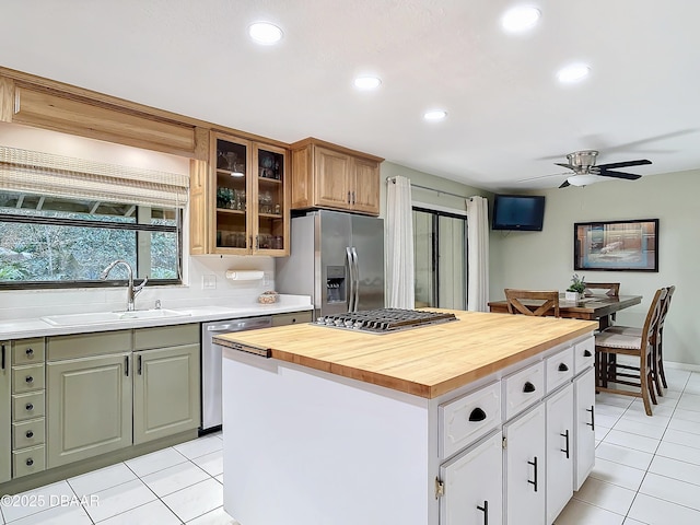 kitchen featuring white cabinets, wood counters, a center island, stainless steel appliances, and a sink