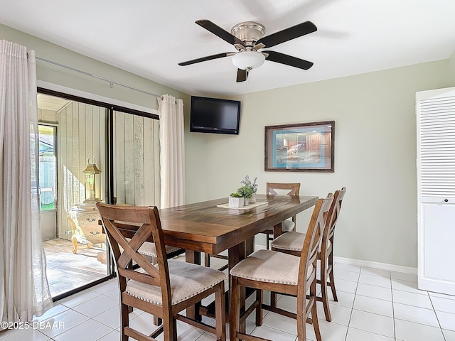 dining space with light tile patterned flooring, a ceiling fan, and baseboards