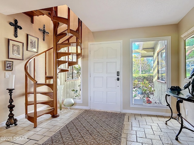 entrance foyer featuring stairs, a textured ceiling, and baseboards