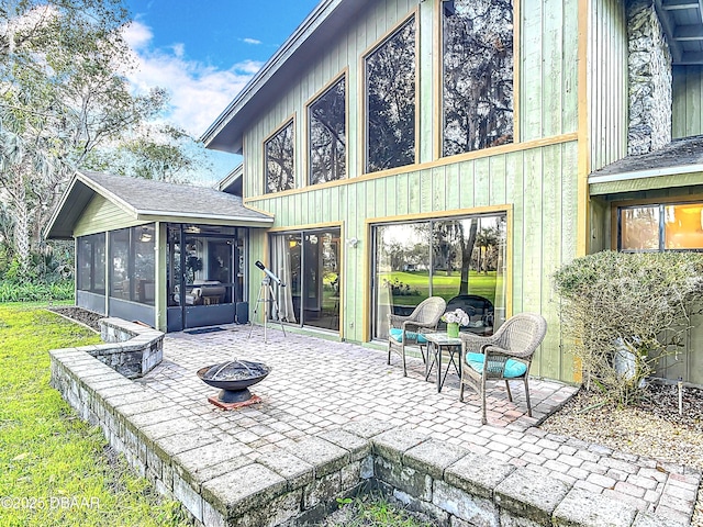 view of patio / terrace with an outdoor fire pit and a sunroom