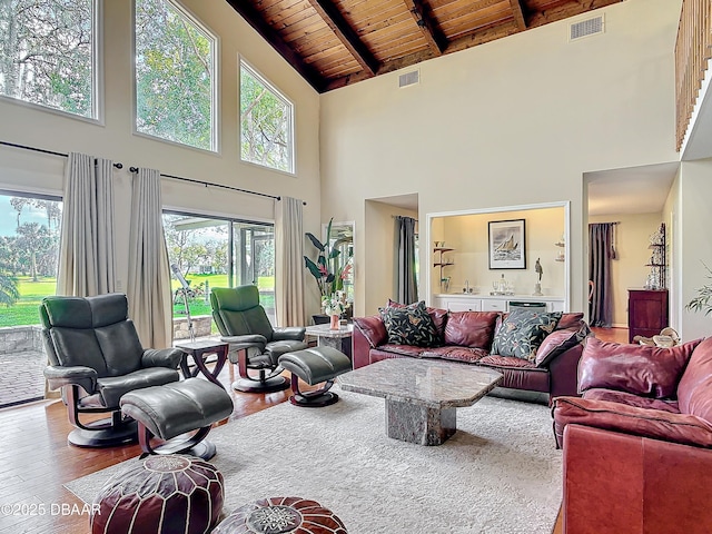 living area with vaulted ceiling with beams, wooden ceiling, wood finished floors, and visible vents