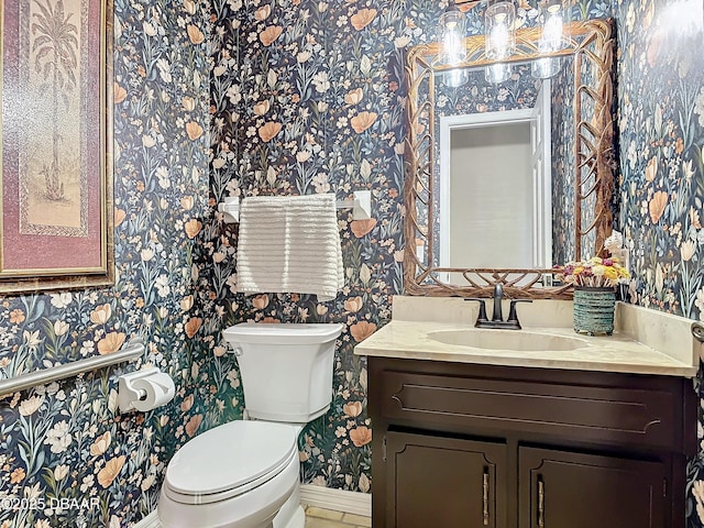 half bath featuring vanity, toilet, wallpapered walls, and baseboards