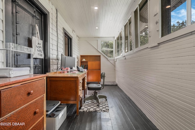 home office with dark wood-type flooring and wood walls