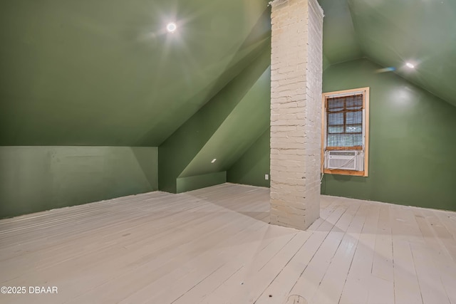 bonus room featuring cooling unit, light hardwood / wood-style flooring, and lofted ceiling