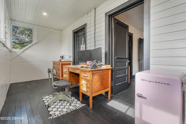 home office with dark hardwood / wood-style floors and wooden walls