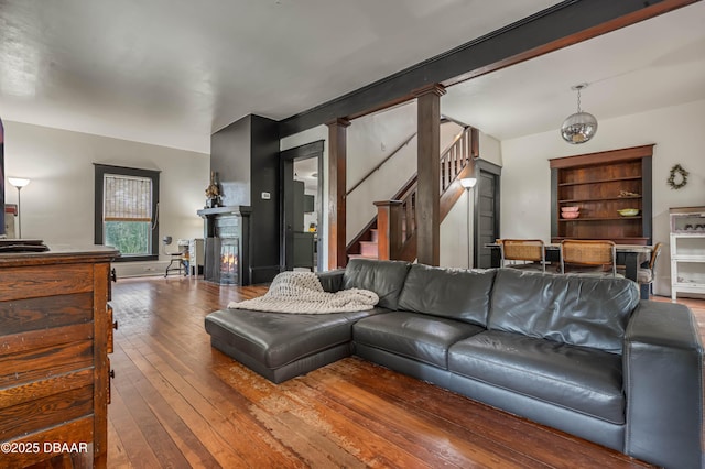 living room featuring a chandelier, built in features, hardwood / wood-style floors, and decorative columns