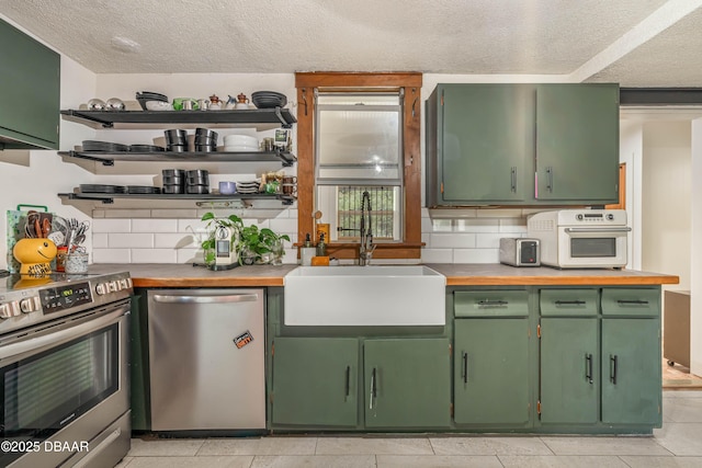 kitchen featuring a textured ceiling, appliances with stainless steel finishes, tasteful backsplash, sink, and green cabinetry