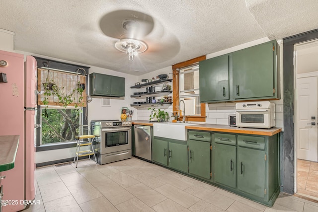 kitchen with green cabinetry, ceiling fan, stainless steel appliances, and sink