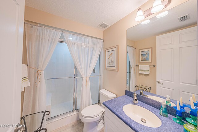 bathroom with wood-type flooring, toilet, a textured ceiling, a shower with curtain, and vanity