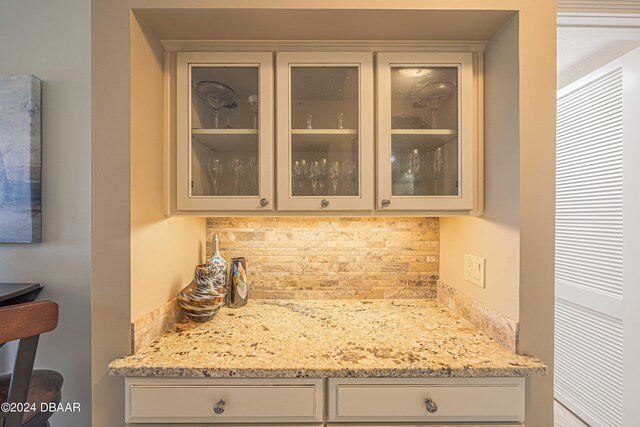 bar featuring light stone countertops and backsplash