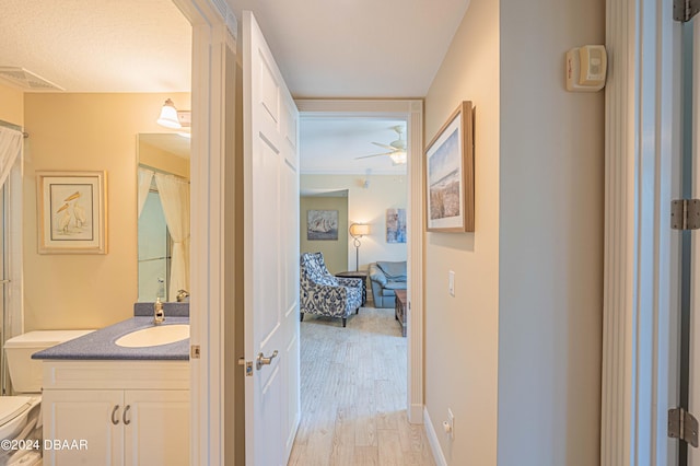 bathroom with a shower with curtain, vanity, hardwood / wood-style floors, toilet, and ceiling fan