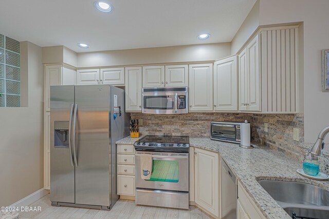 kitchen featuring light stone countertops, sink, appliances with stainless steel finishes, and tasteful backsplash