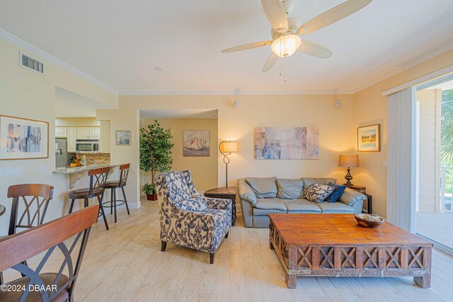 living room with ornamental molding, light hardwood / wood-style floors, and ceiling fan