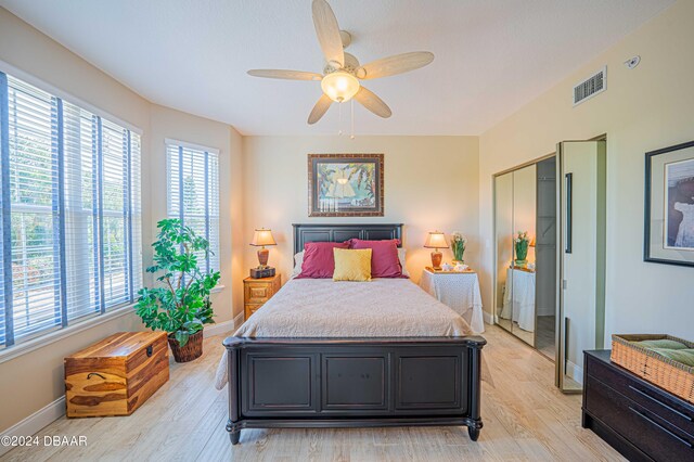 bedroom with light wood-type flooring, ceiling fan, and a closet