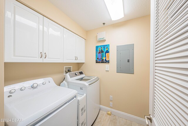 washroom with cabinets, electric panel, a textured ceiling, and washer and clothes dryer