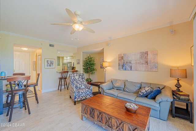 living room featuring ornamental molding, light hardwood / wood-style floors, and ceiling fan