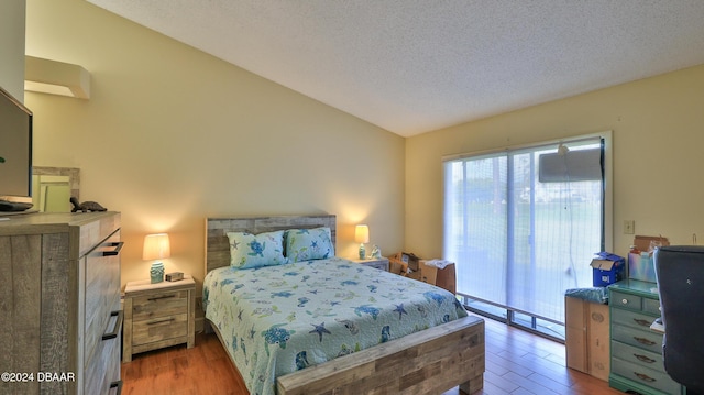 bedroom with vaulted ceiling, hardwood / wood-style floors, and a textured ceiling