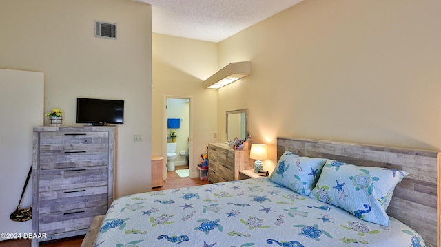 bedroom featuring wood-type flooring, a textured ceiling, and ensuite bath