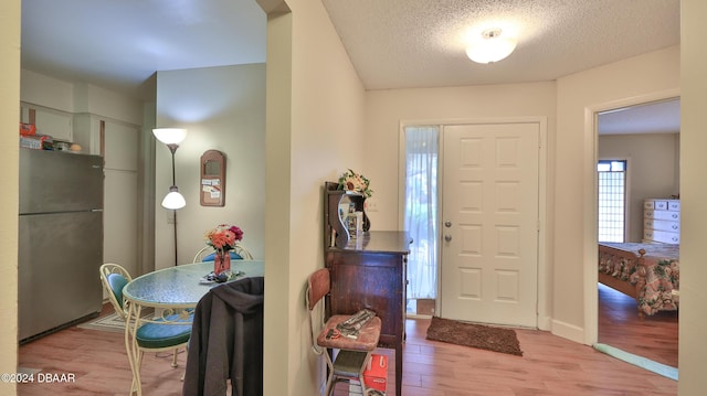 foyer entrance with a textured ceiling and light hardwood / wood-style flooring