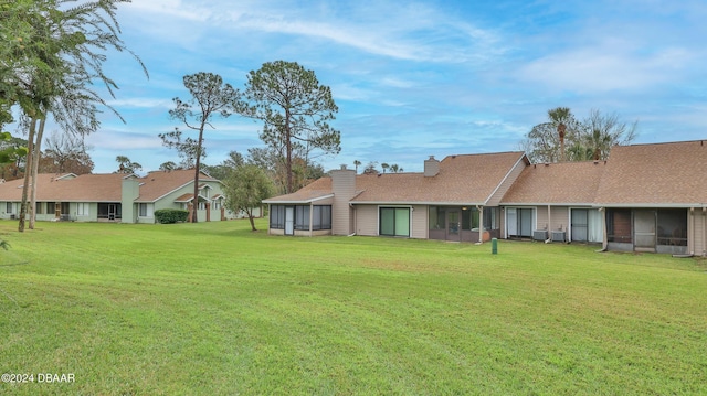 rear view of property with a lawn and a sunroom