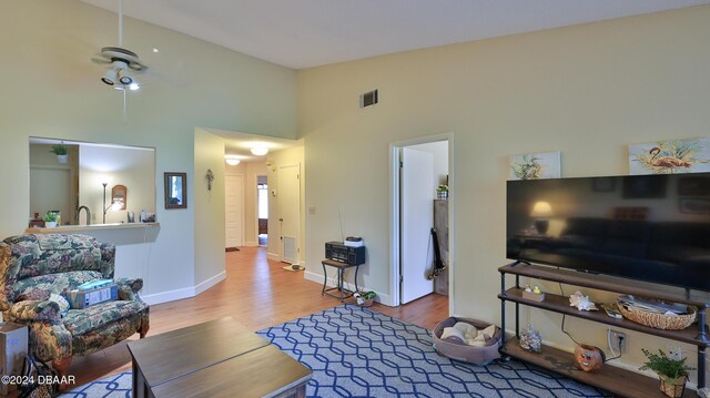 living room with hardwood / wood-style floors, ceiling fan, and high vaulted ceiling