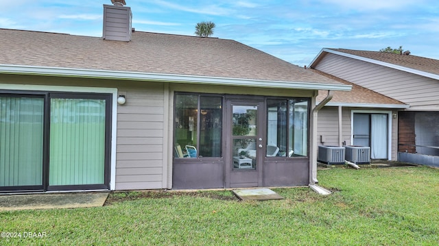 back of property with cooling unit and a yard