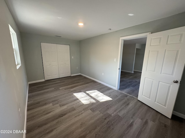 unfurnished bedroom featuring a closet and dark hardwood / wood-style floors