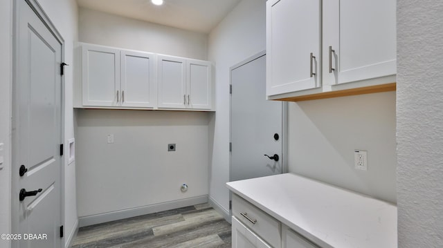 clothes washing area featuring light hardwood / wood-style flooring, hookup for an electric dryer, and cabinets