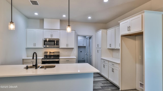 kitchen with sink, appliances with stainless steel finishes, white cabinetry, and hanging light fixtures