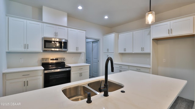 kitchen featuring sink, white cabinets, an island with sink, hanging light fixtures, and appliances with stainless steel finishes