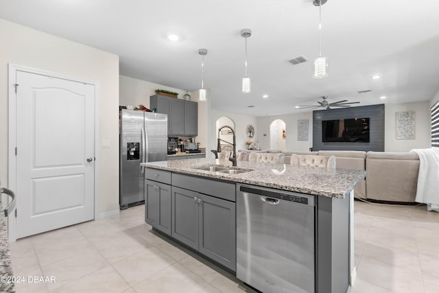 kitchen with ceiling fan, sink, gray cabinets, a kitchen island with sink, and appliances with stainless steel finishes