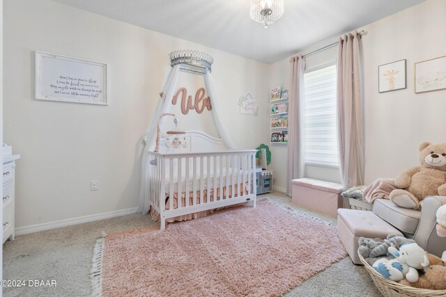 carpeted bedroom with an inviting chandelier and a nursery area