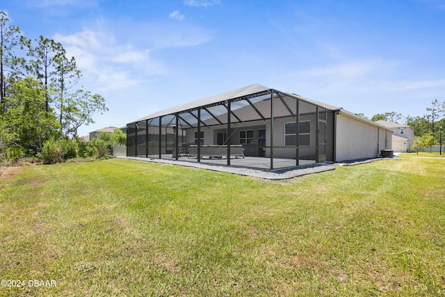 back of house with a lanai, a patio area, and a lawn