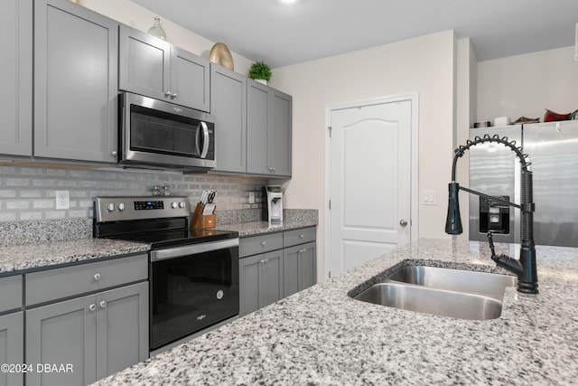 kitchen with backsplash, gray cabinetry, sink, and appliances with stainless steel finishes