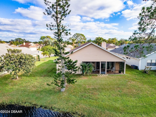 rear view of property featuring a yard and a sunroom