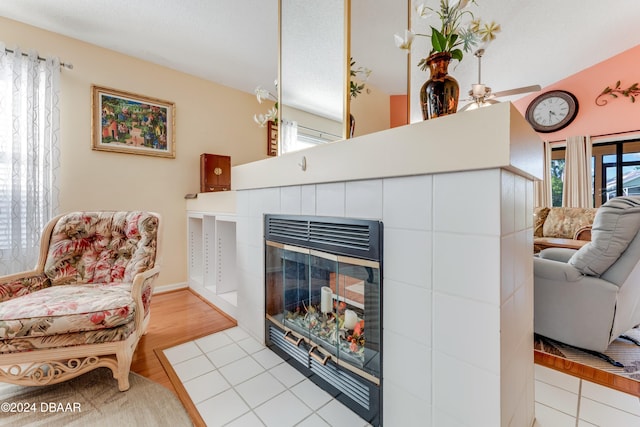 living room featuring a fireplace, ceiling fan, and light hardwood / wood-style flooring