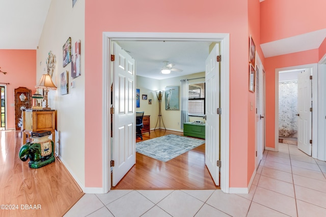 corridor featuring plenty of natural light, light wood-type flooring, and vaulted ceiling