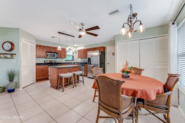 tiled dining area with sink and ceiling fan with notable chandelier